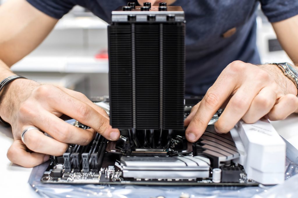 Techniker montiert CPU-Kühler auf einem Mainboard – professionelle Hardware-Installation und Wartung für maximale Systemleistung.